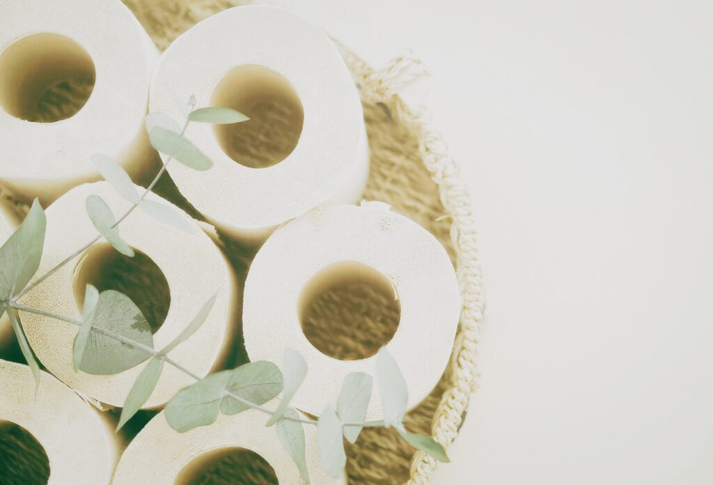basket full of bamboo toilet paper rolls with a eucalyptus leaf on top